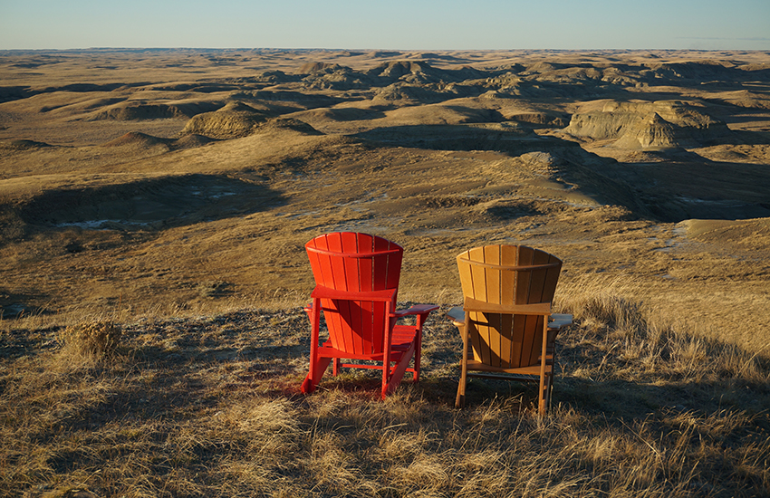 Two chairs all alone in a long field