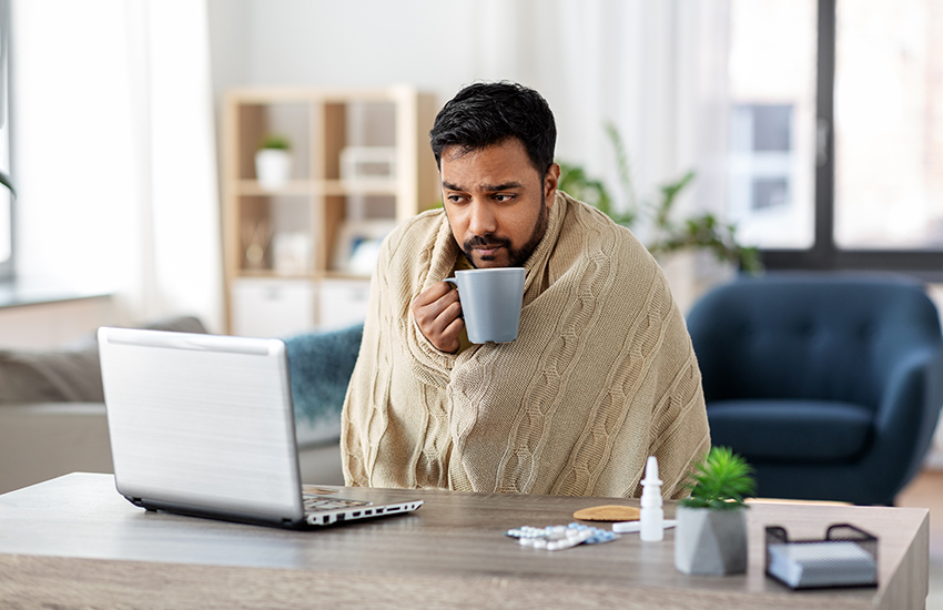 A sick worker sitting at his desk with a blanket