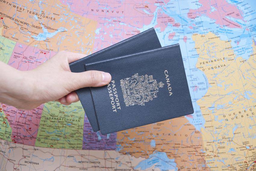 Two Canadian passports in front of a map of Canada