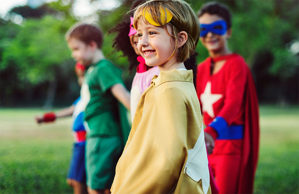 Children dressed as superheroes participating in an outdoor community activity. 