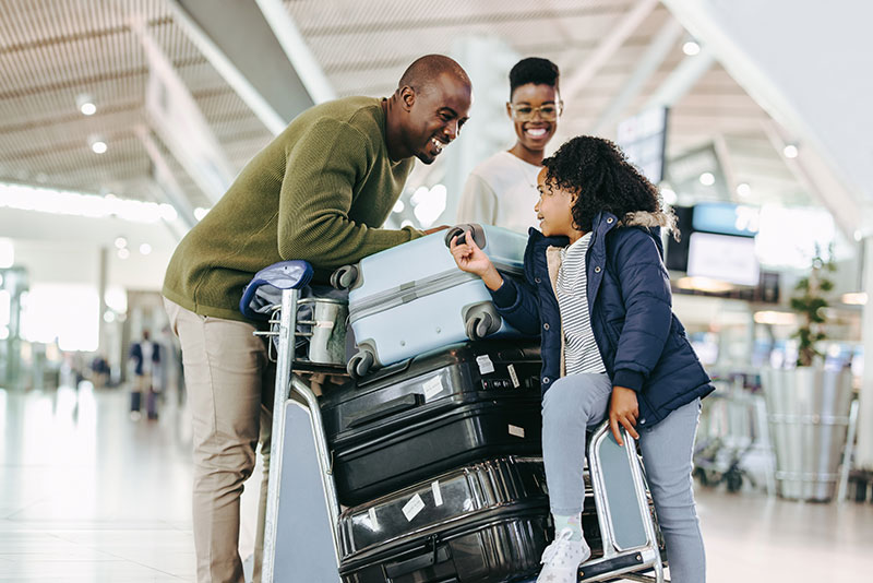 Tourist family with luggage trolley at airport