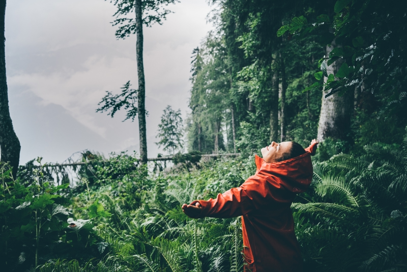 Young woman with raincoat smiles under the rain