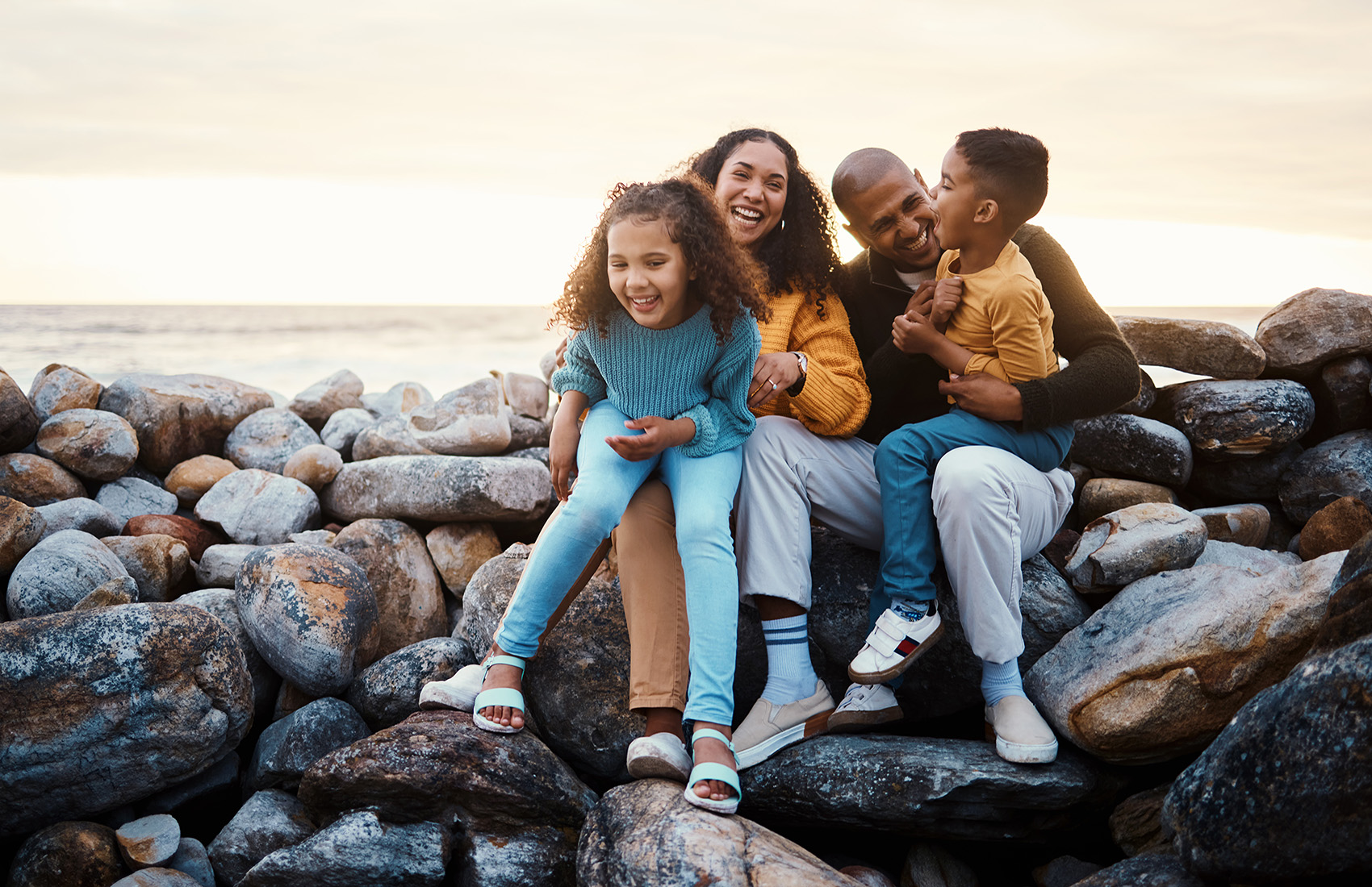 Four people sitting on rocks near the sea