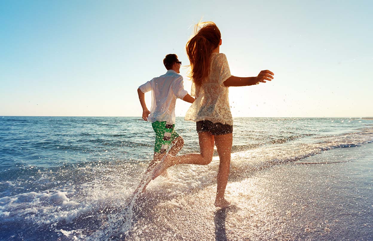 Happy young couple enjoying the sea on a beach getaway.