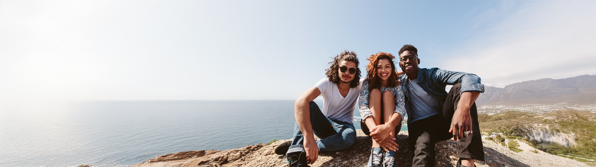 Three young people reach the top of a mountain
