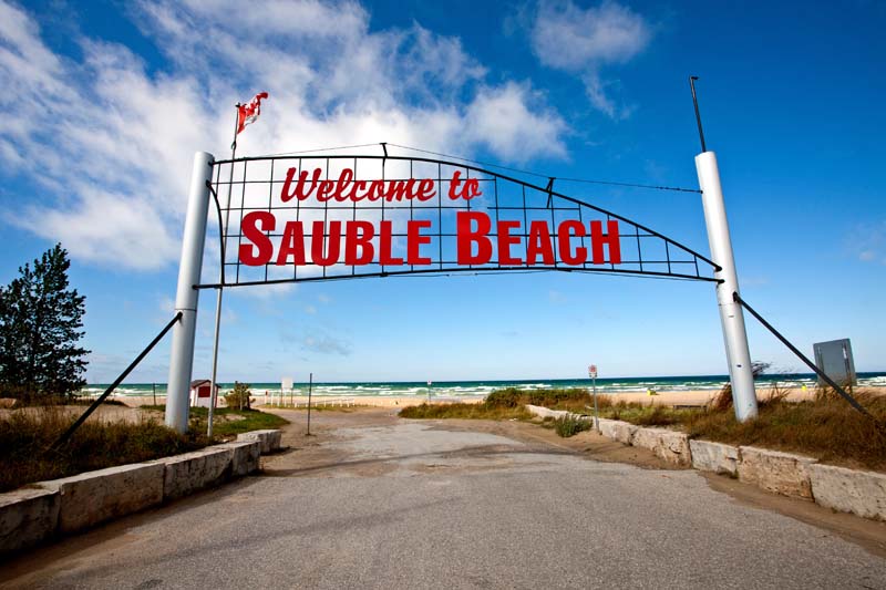 Sauble Beach sign with sea and blue sky in the background