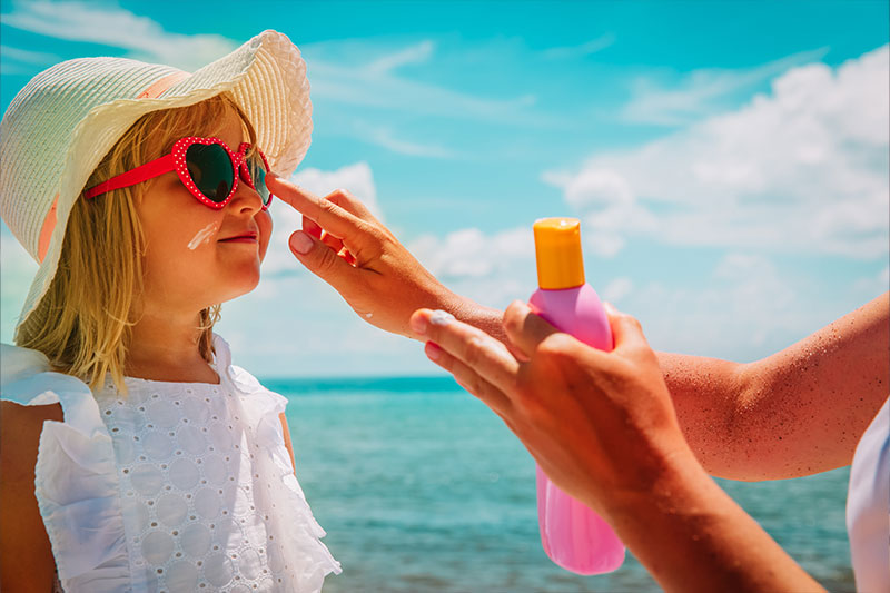 Little girl on the beach with sunscreen