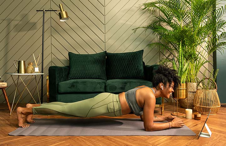 Woman doing a plank exercise in a stylish living room setting.