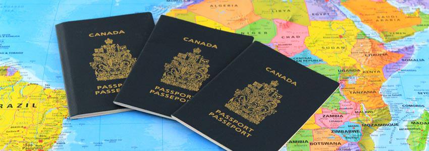 Three canadian passports spread on top of the world map